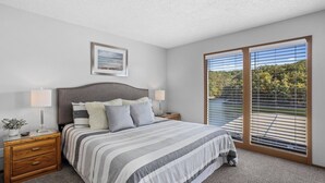 Een slaapkamer met een groot bed, twee nachtkastjes, een raam met zonwering en een lijst met een afbeelding aan de muur.