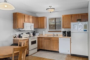 A compact kitchen with wooden cabinets, a microwave, a stove, a dishwasher, and a refrigerator. - Lazy Days B-01 - Two Bedroom Apartment, Sleeps 6 (Osage Beach)
