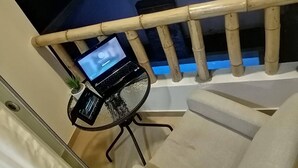 A laptop on a small table next to a staircase with a bamboo railing. - Paracas Guest House (Paracas)