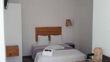 Un dormitorio con cabecera de madera, una cama con ropa de cama blanca, una mesita de noche, un escritorio y una silla.