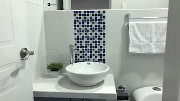A bathroom with a white sink, blue mosaic tiles, a small potted plant, and a white toilet.