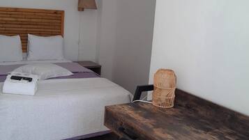 Un dormitorio con cama, mesita de noche, silla y escritorio con lámpara.