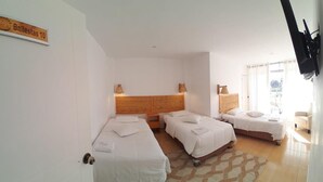 A hotel room with two beds, a wooden headboard, a patterned rug, and a television mounted on the wall. - Paracas Guest House (Paracas)