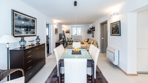 Un salon moderne avec un coin repas, comprenant un canapé, une table basse et un téléviseur.