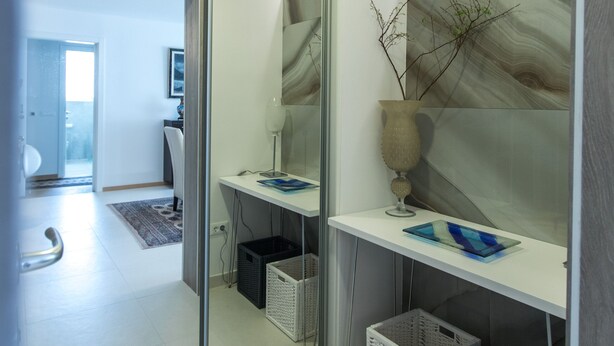 Un baño moderno con mampara de vidrio, un espejo, un florero y dos cestas.