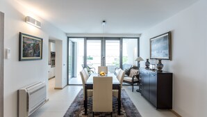 Un comedor moderno con una mesa dispuesta para cuatro, un armario negro y un gran ventanal con vistas al exterior.