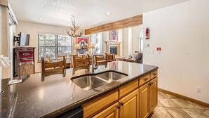 A spacious kitchen with granite countertops, wooden cabinets, and a central island with a sink.