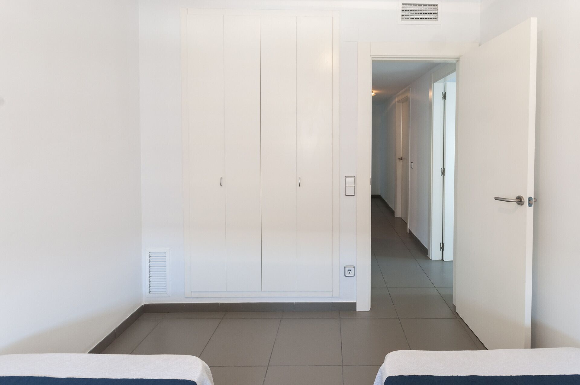 Ein Hotelzimmer mit großem Schrank, einem Bett und einem durchgegangene Tür erkennbaren Badezimmer.