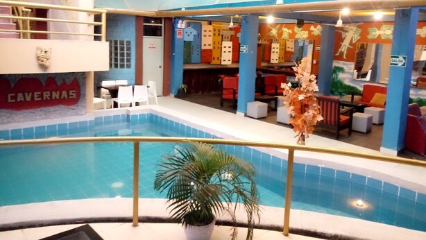 An indoor swimming pool with a seating area, a bar, and a sign reading "CAVERNAS". - Hotel Daylu (Punchana)