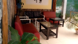 A seating area with a sofa, chairs, and a table. There is a wall-mounted artwork of a horse. - Hotel Daylu (Punchana)