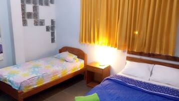 Un dormitorio con dos camas, una mesita de noche, una lámpara de pared y un ventanal con cortinas.