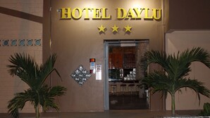 The exterior of Hotel Dayalu with a sign above the entrance, a bar area visible through the doorway, and two palm trees in front. - Hotel Daylu (Punchana)