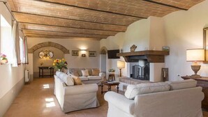 A spacious living room with a fireplace, a sofa set, and a dining area with a table and chairs. - Villa I Cipressini Tuscany Private luxury pool spa (Pienza)