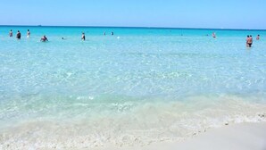 Une plage avec une eau turquoise cristalline et un rivage sablonneux.
