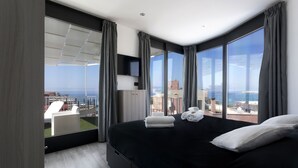 Una habitación de hotel moderna con una cama grande, un televisor de pantalla plana y un balcón con vistas a la ciudad.