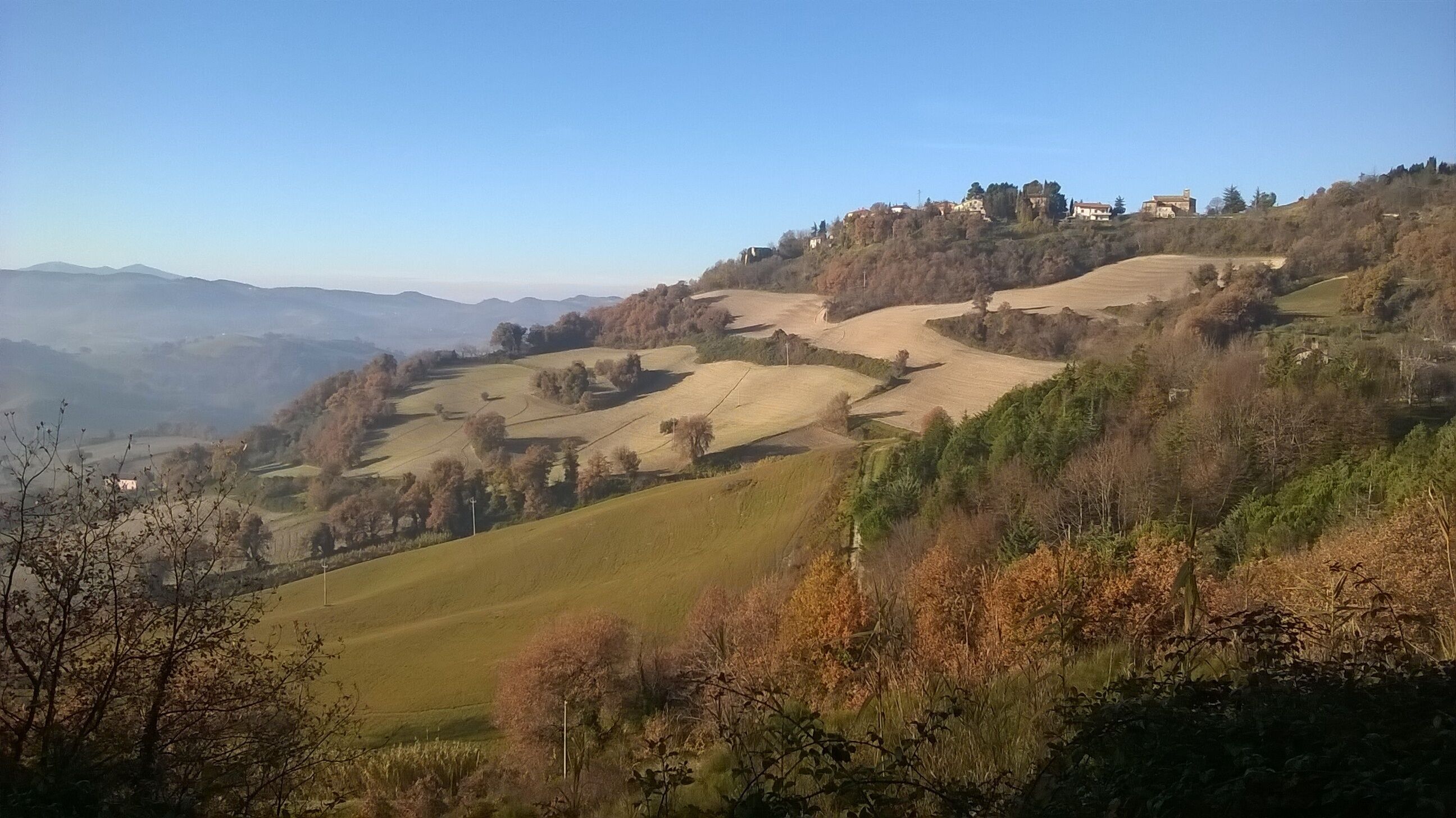 Une vue panoramique de collines ondoyantes parsemées de maisons, probablement dans un cadre rural.
