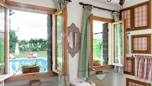 Un dormitorio con vista a una piscina, un radiador, una mesita de noche con una cesta y una cama con colcha de cuadros.