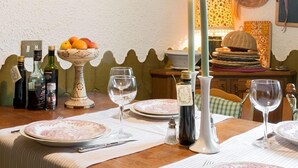 Una mesa de comedor dispuesta con platos, vasos y velas, rodeada de adornos y una cesta de frutas.