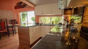 Una cocina moderna con una isla grande, armarios blancos y vistas a espacios verdes.