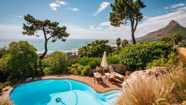 Una piscina con vista al océano y una montaña al fondo.