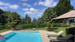A rectangular swimming pool with clear blue water, surrounded by a tiled deck. There are lounge chairs and a small pavilion with a roof. - House / Villa - ARBONNE (Arbonne)