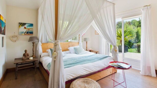 A four-poster canopy bed with a view of greenery outside. - House / Villa - ARBONNE (Arbonne)