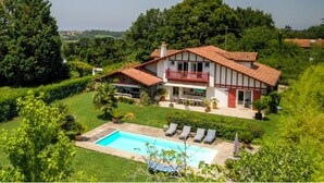 A two-story house with a red-tiled roof, a balcony, and a swimming pool with lounge chairs. - House / Villa - ARBONNE (Arbonne)