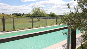 Une piscine dotée d’une terrasse en bois et offrant une vue sur un paysage verdoyant.