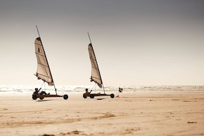 Two sailboats on a sandy beach with the ocean in the background.