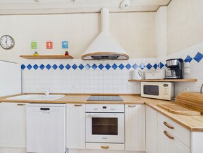 Eine Küche mit weißen Schränken, einem Geschirrspüler, einem Backofen, einer Mikrowelle und einer Kaffeemaschine.