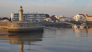 A waterfront area with a lighthouse, a bridge, and residential buildings.