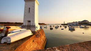 A coastal harbor with boats docked, a white tower, and a calm sea. - 150m from the beach - Maison vendéenne for 6 (Bretignolles-sur-Mer)