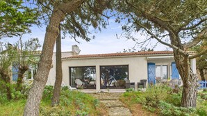 A house with a stone pathway leading to a glass door, surrounded by greenery and trees. - 150m from the beach - Maison vendéenne for 6 (Bretignolles-sur-Mer)