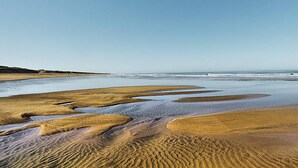 A beach with wet sand patterns and a clear sky.