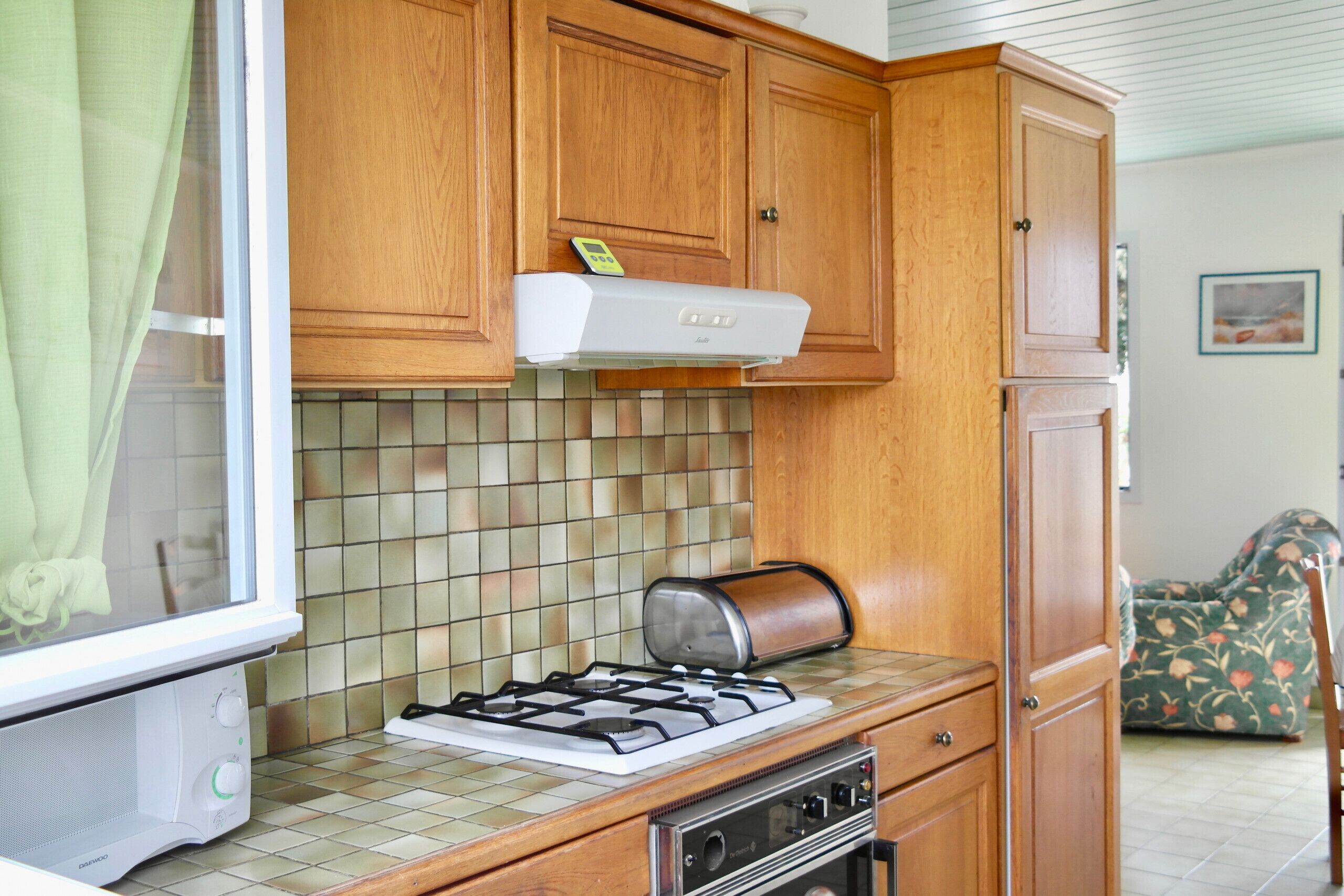 A compact kitchen with wooden cabinets, a gas stove, a toaster, and a microwave.