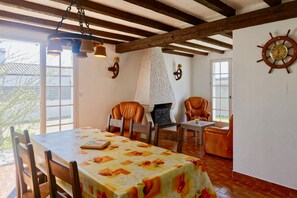 A dining area with a table set for two, surrounded by leather chairs, a fireplace, and a ship's wheel decoration on the wall. - House for 4 - Garden - 400m from Lutins beach (Noirmoutier-en-l´Ile)