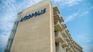 A building with the name 'Akrópolis' on its facade, featuring a modern architectural style with a prominent balcony on the right side. - Acropolis Oceanfront Resort (North Wildwood)