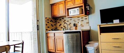 A kitchen with wooden cabinets, a microwave, a dishwasher, and a TV.