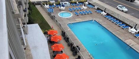 A hotel with a pool, lounge chairs, and a view of the ocean.