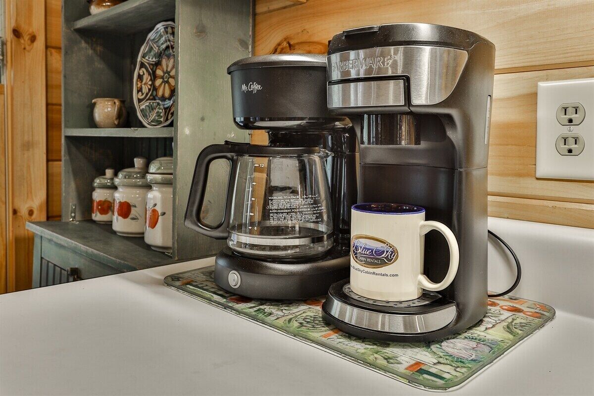 A kitchen with a coffee maker, a mug, and decorative items on shelves.