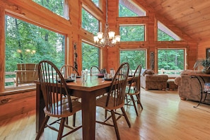 A wooden interior with a dining table, chairs, and a chandelier.