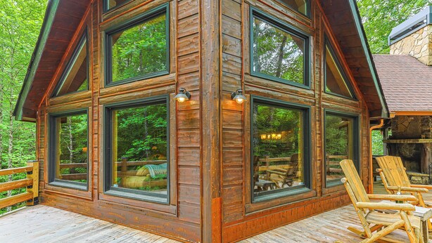 A cabin with large windows, a deck, and wooden furniture. - Serenity on The Mountain | Blue Ridge, GA (Blue Ridge)