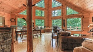 A log cabin interior with a dining area, a fireplace, and large windows. - Serenity on The Mountain | Blue Ridge, GA (Blue Ridge)