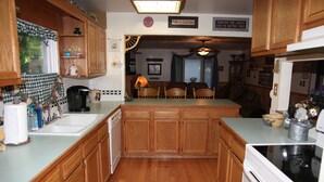 Una cocina con armarios de madera, una isla central y un comedor con sillas.