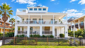 A two-story building with balconies, a fenced front yard, and a clear sky. - Dolphin Beach | Ocean-View Balcony & 1-Min Walk (Palm Coast)