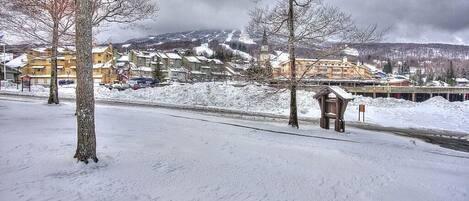 A snow-covered landscape with buildings, a bridge, and a snow-covered road.