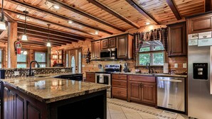 A spacious kitchen with granite countertops, stainless steel appliances, and wooden cabinetry.