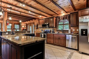 A spacious kitchen with granite countertops, stainless steel appliances, and wooden cabinetry.