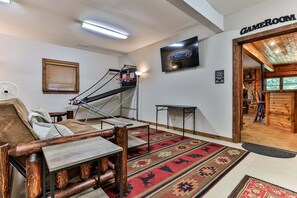 A room with a basketball hoop, a table tennis table, a wooden bench, a patterned rug, and a sign indicating a table tennis room.