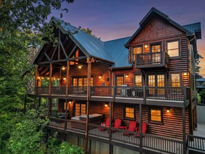 A multi-story log cabin with a balcony and outdoor seating area.